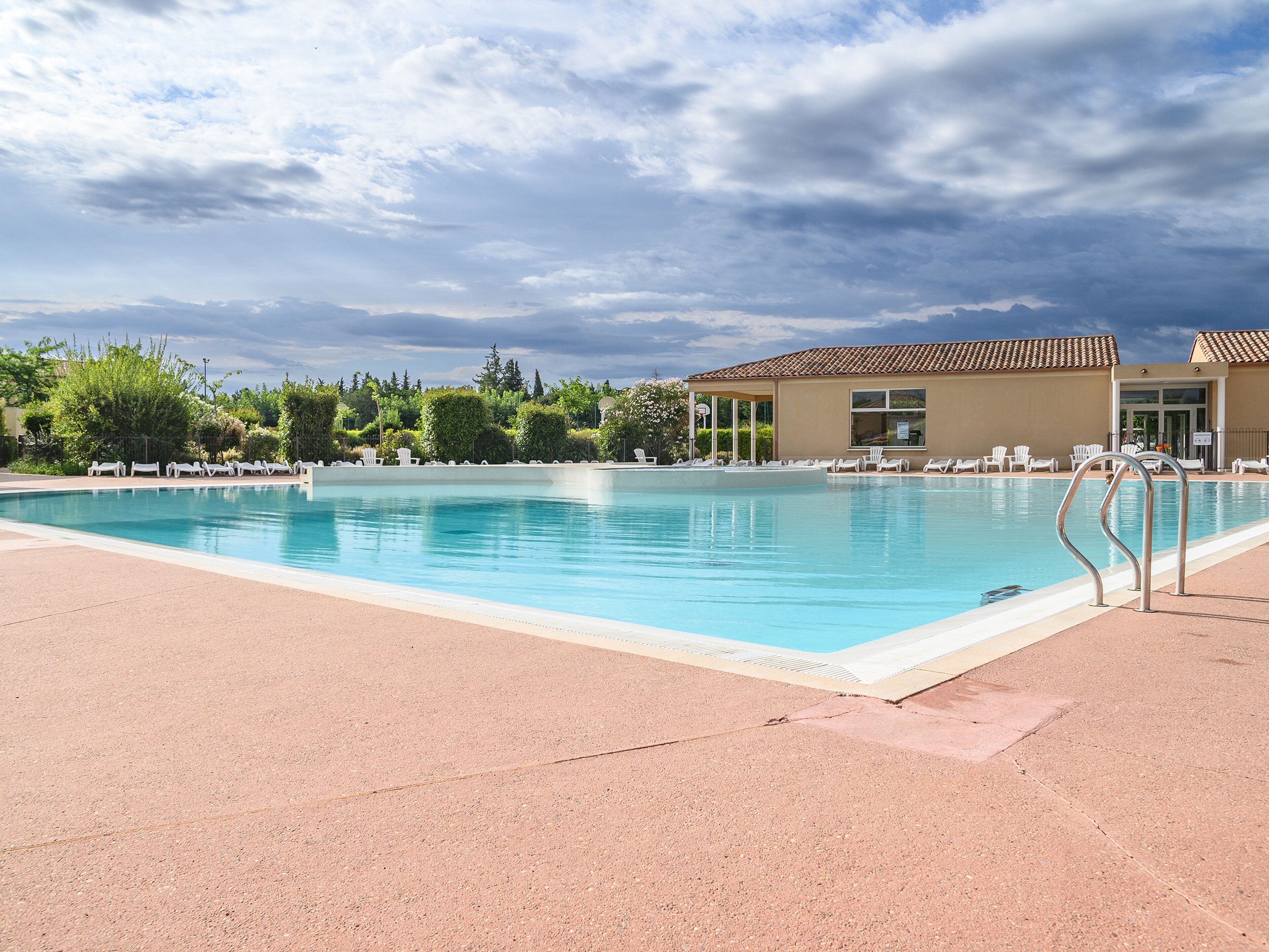 Una piscina nítida amb gandules i una zona coberta.