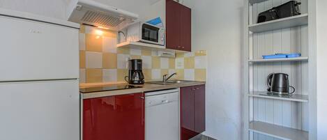 A compact kitchen with a refrigerator, microwave, coffee maker, and a dishwasher.