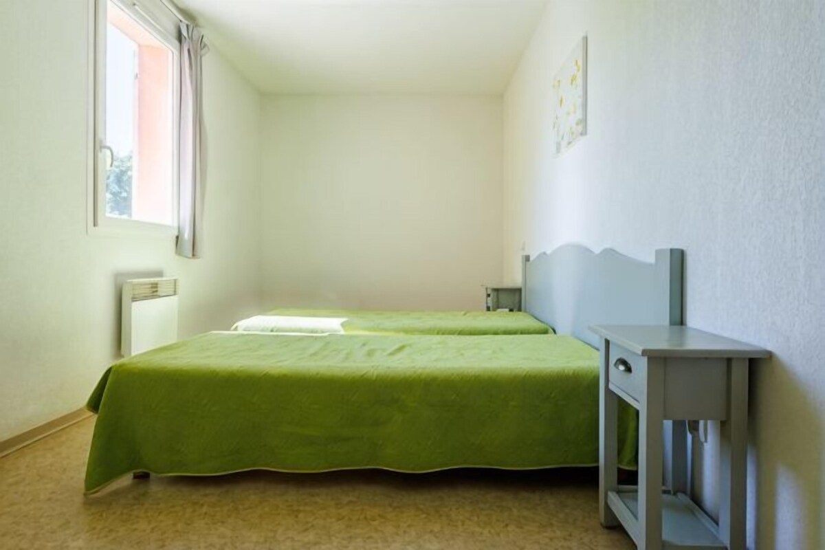 Una habitación con dos camas, un escritorio, un radiador y una ventana.