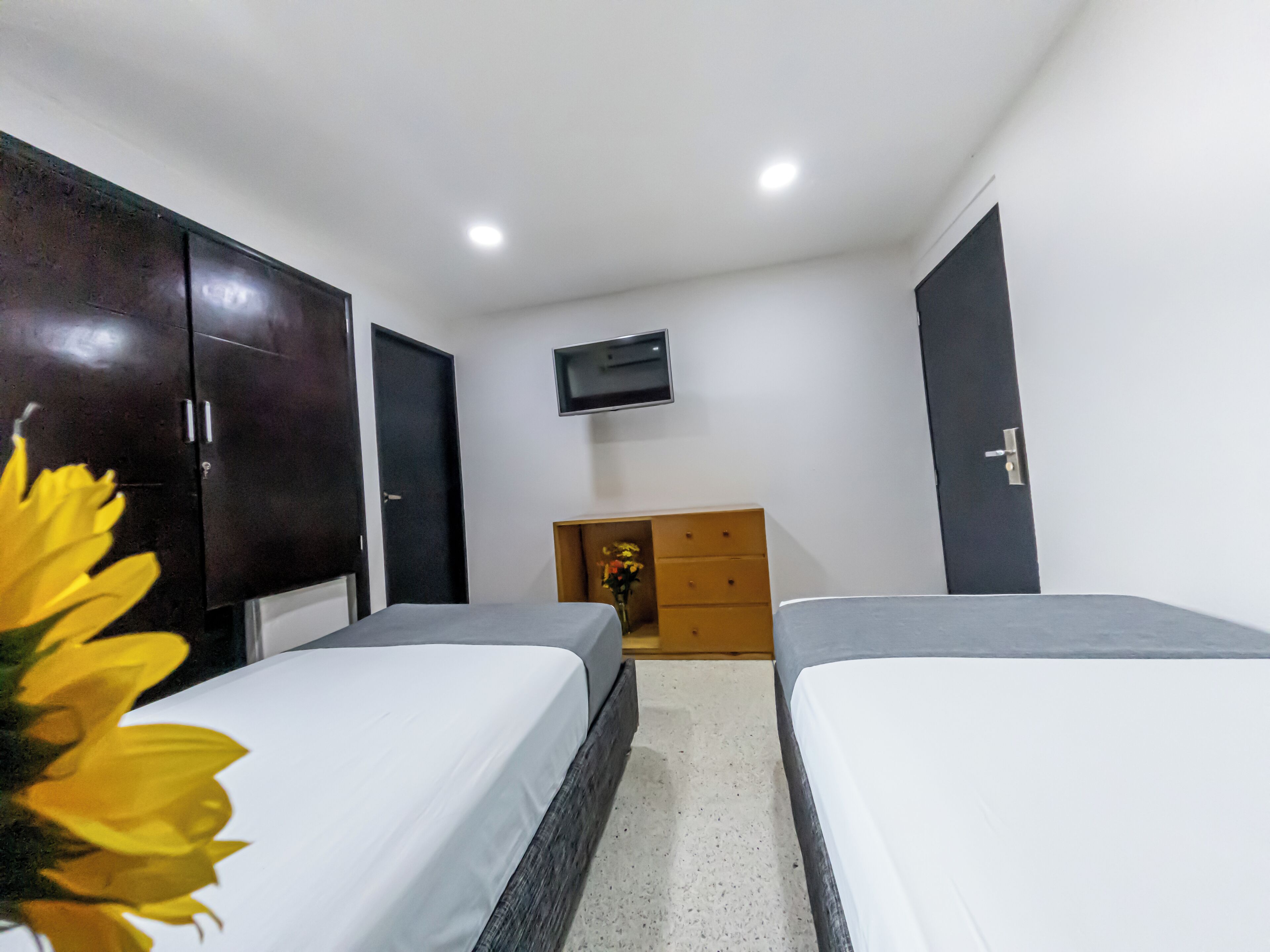 Un dormitorio con dos camas, un televisor en la pared y un aparador de madera.