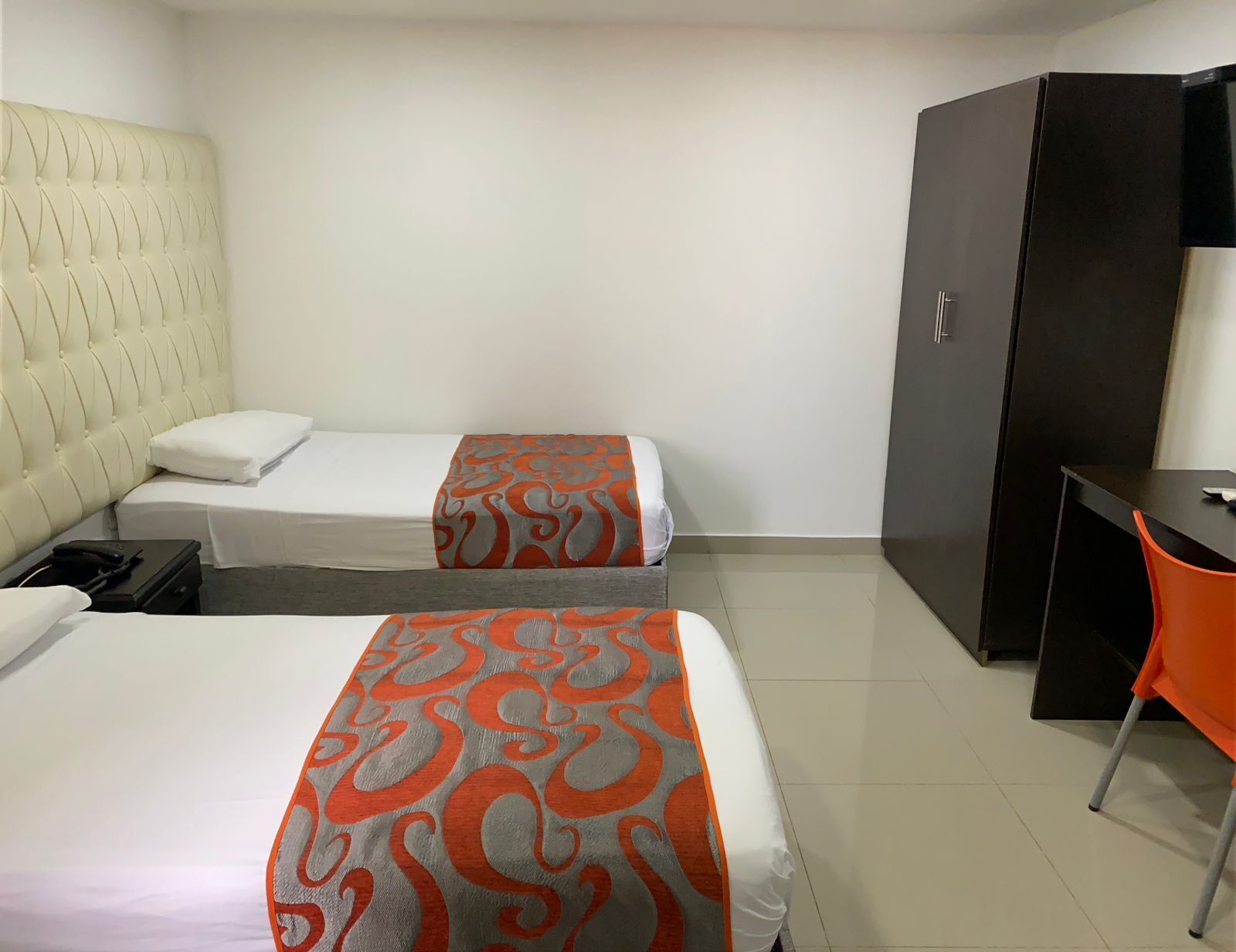Una habitación de hotel con dos camas, un escritorio y un armario.
