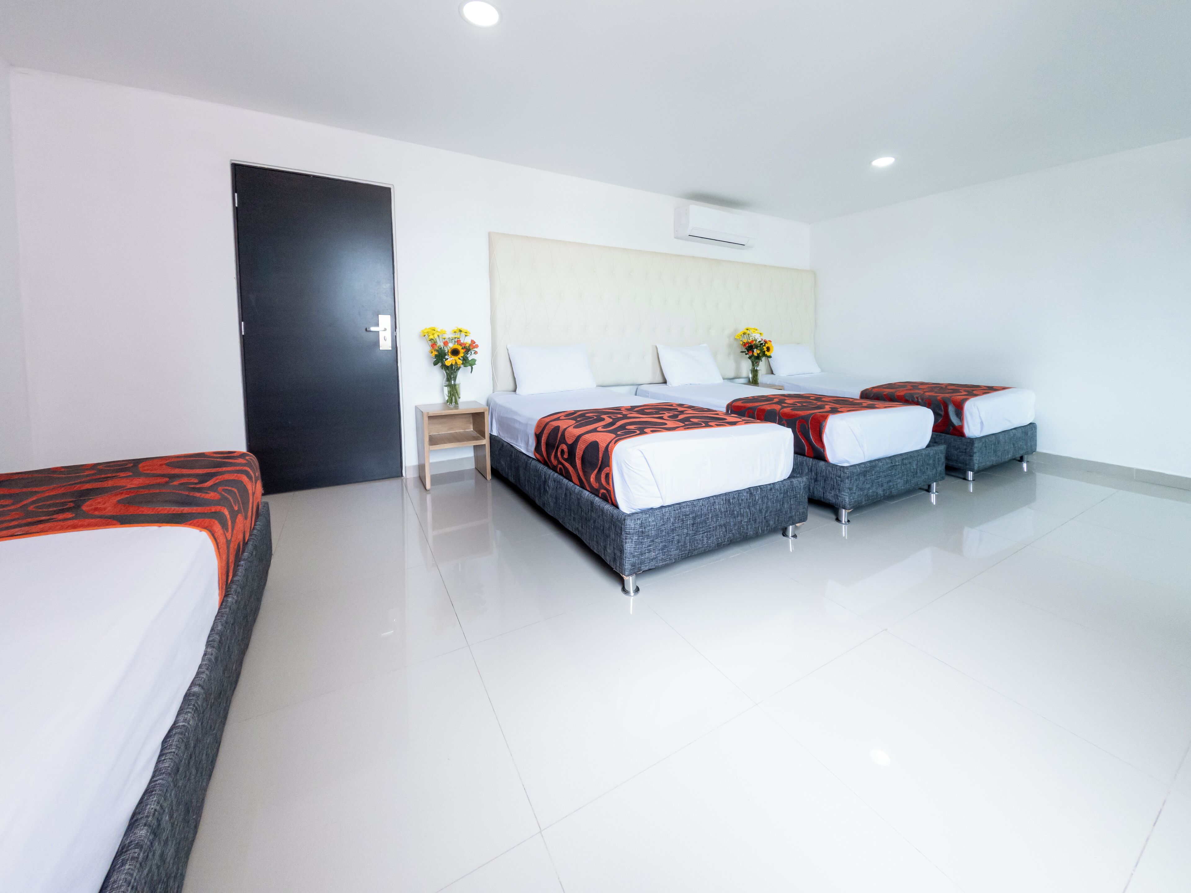 A hotel room with two beds, a nightstand, and a vase with flowers.