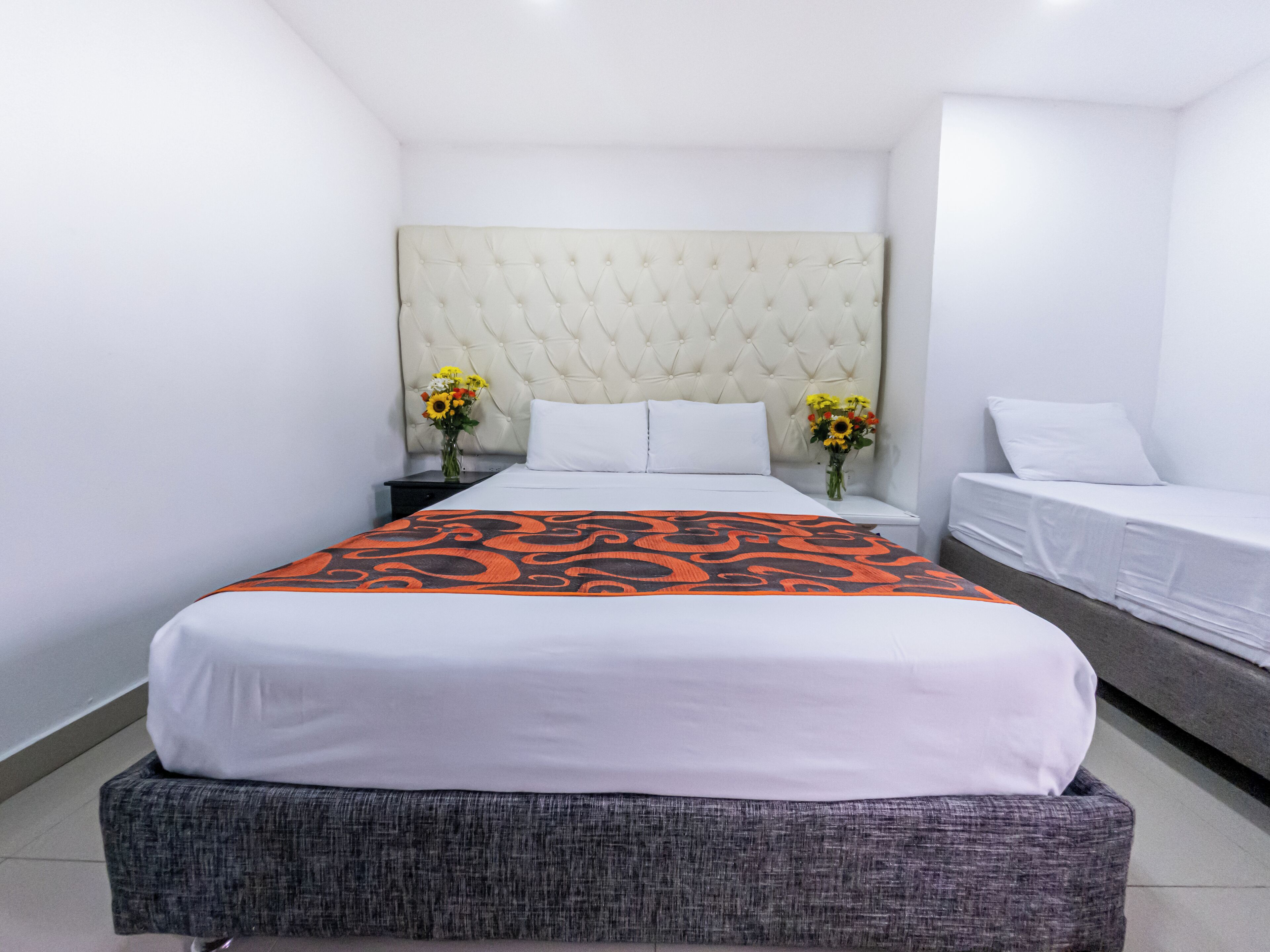 A hotel room with a large bed, two nightstands, a sofa, and a tufted headboard.