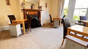 A dining area with a fireplace, wooden furniture, and a chandelier. - Alcuin Lodge (York)