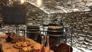 Un comedor rústico con una larga mesa de madera dispuesta con copas de vino, botellas y una variedad de platos.