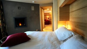 Una habitación de hotel con cama, chimenea y cabecero de madera.