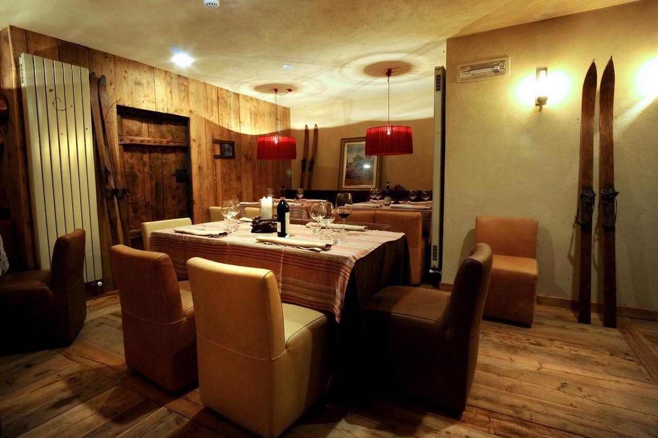 Un comedor con paredes de madera, una mesa dispuesta con copas de vino y platos, y sillones de cuero.
