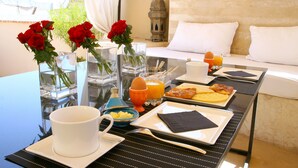 Una mesa de desayuno con diversas opciones de comida, un jarrón con rosas rojas y un farol tradicional.