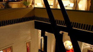 Un edificio de varios niveles con balcón, una escalera y vista al mar al atardecer.