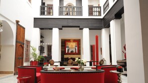 Un vestíbulo amplio con una zona de estar central, un candelabro y una decoración en tonos rojo y negro.