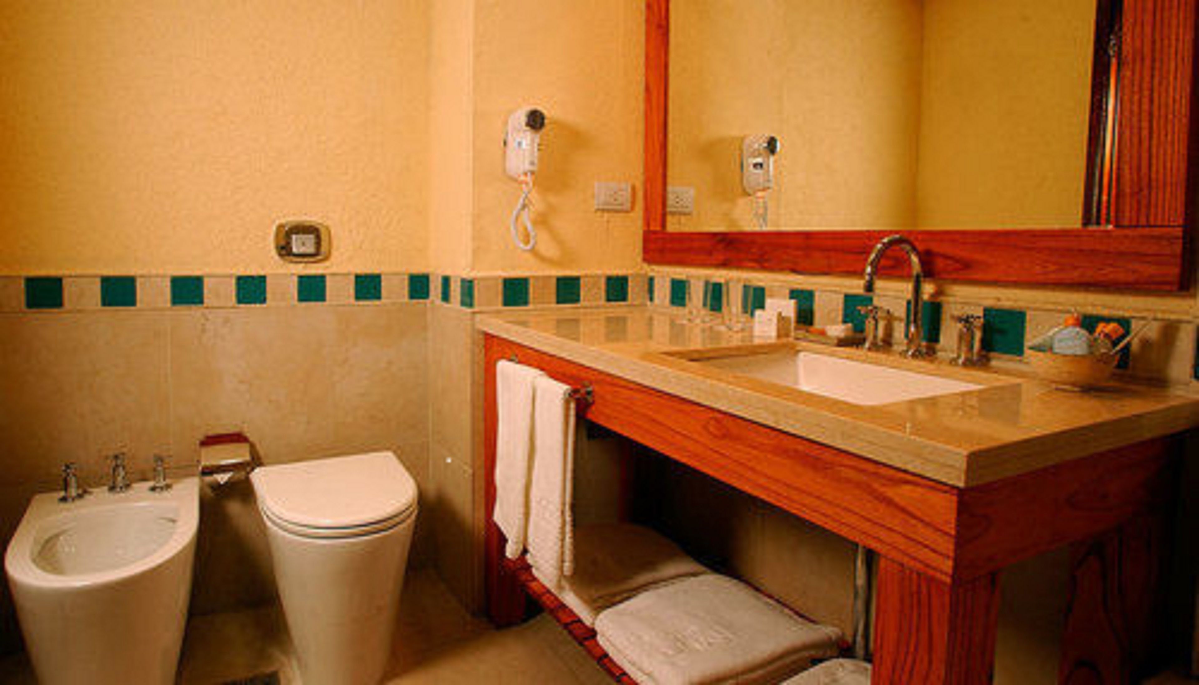A bathroom with a sink, two toilets, a mirror, and a towel rack.