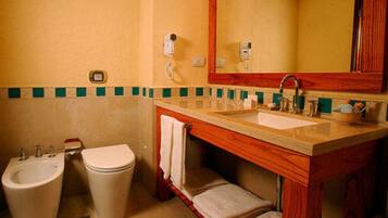 A bathroom with a sink, two toilets, a mirror, and a towel rack.
