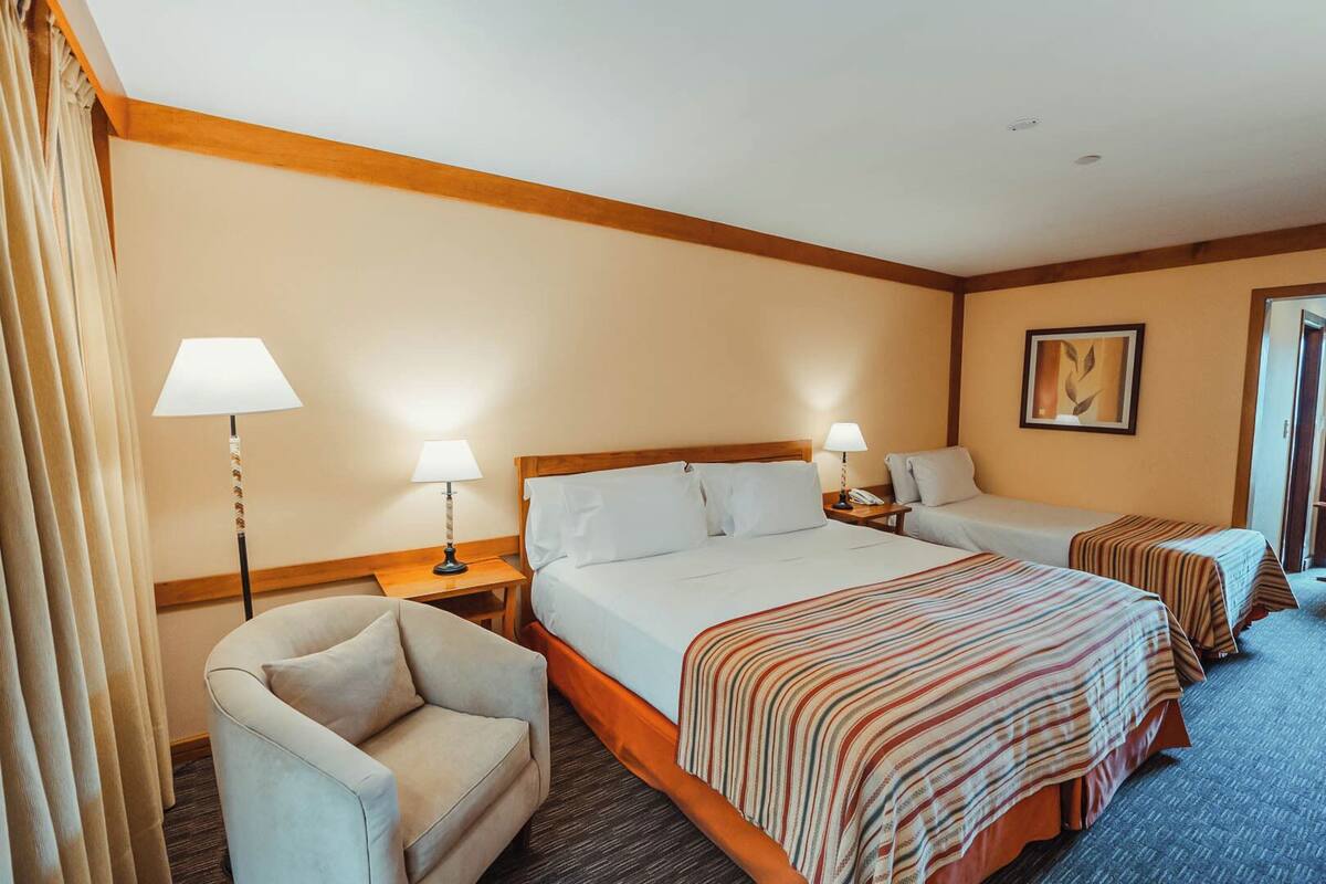 Une chambre d’hôtel avec un grand lit, deux tables de chevet, une chaise et un bureau.