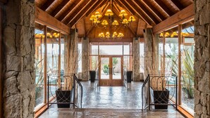Eine großzügige Lobby mit hoher Decke, Steinwänden und einem zentralen Kronleuchter.