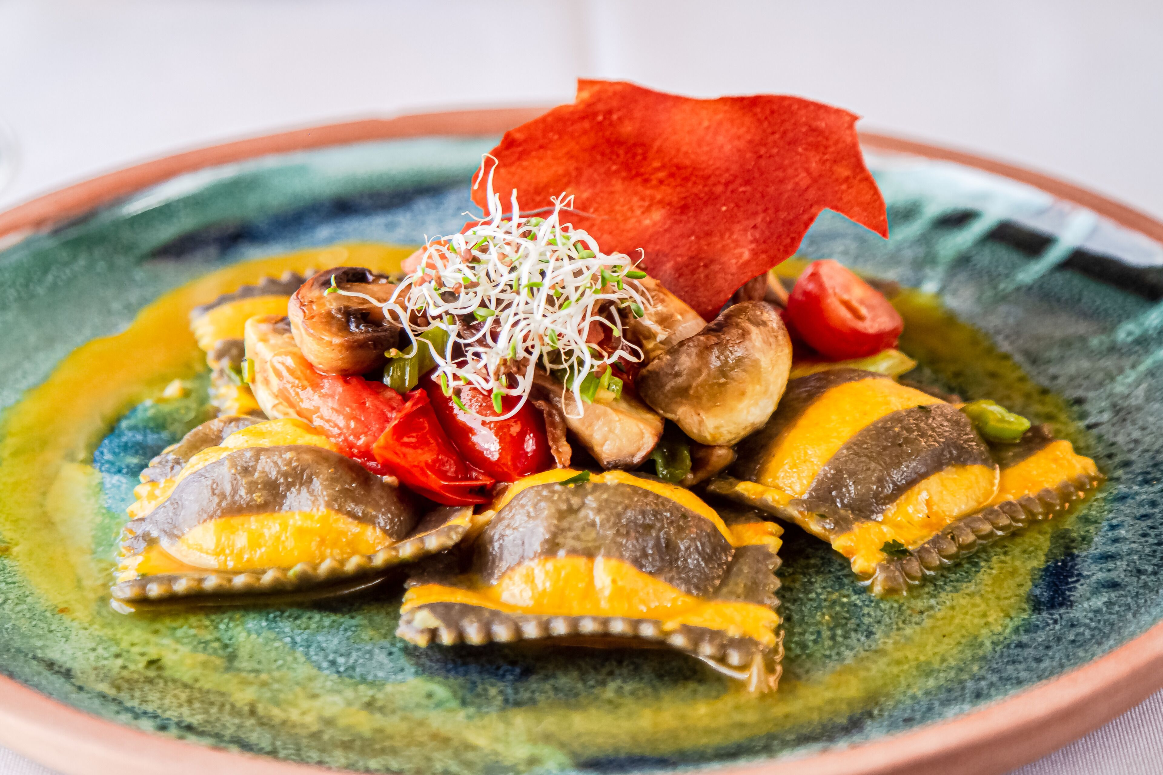 A colorful dish with various vegetables and a red garnish on a plate.