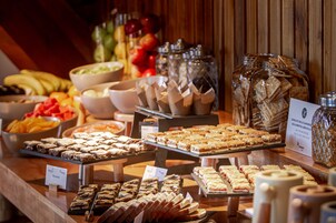 Un bufé con diferentes opciones de comida, incluyendo frutas, pasteles y bocadillos.