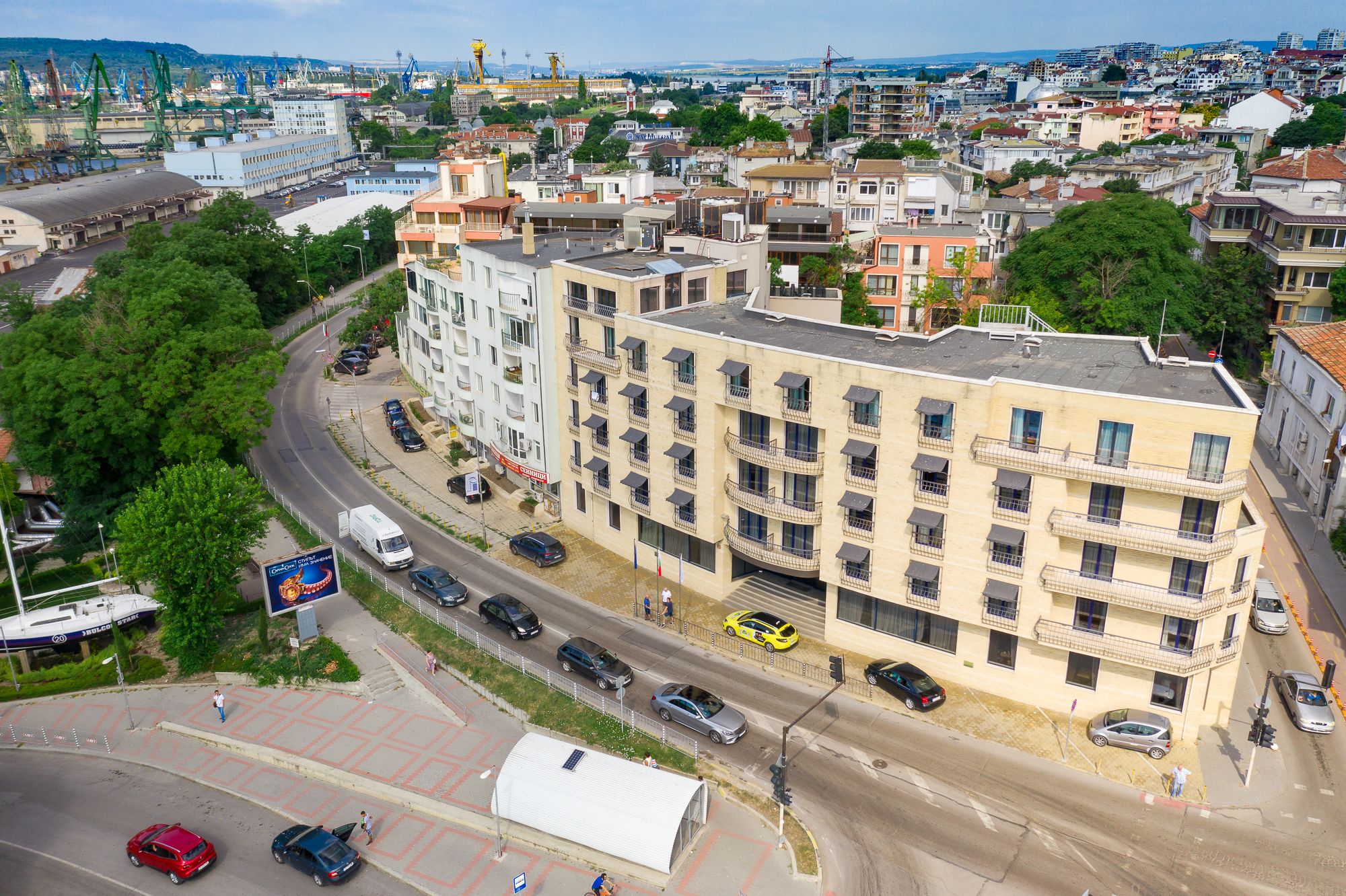 Un edificio de varios pisos con balcones, un estacionamiento y vistas del paisaje urbano circundante.