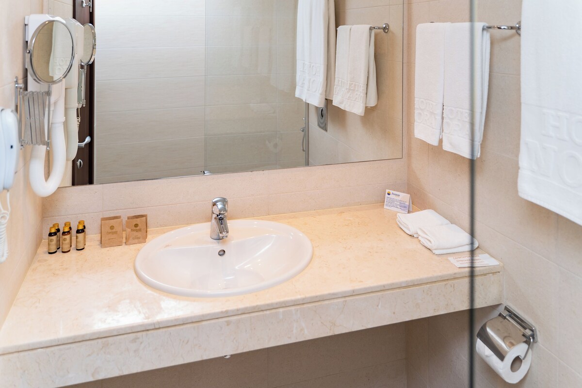 A bathroom with a sink, mirror, and towel rack.