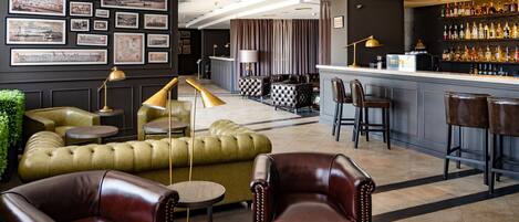A bar area with leather seating, a bar counter, and a wall decorated with framed pictures.