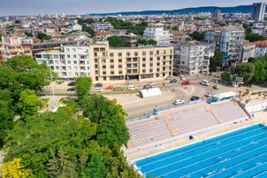 Un edificio grande con varios pisos, rodeado de árboles y una piscina.