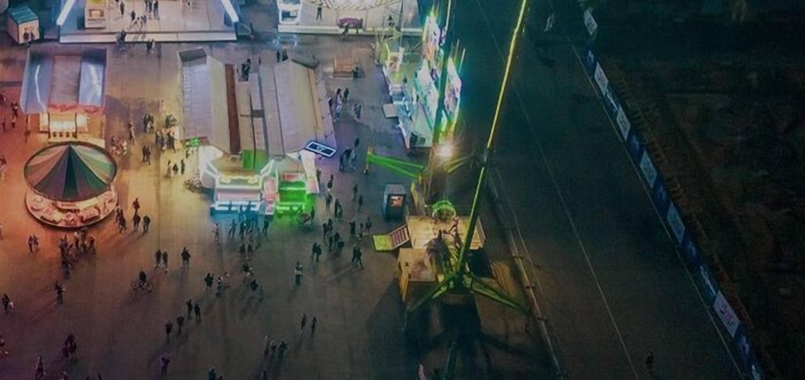 An aerial view of a busy urban square with a carousel, a large open space, and a prominent green structure.