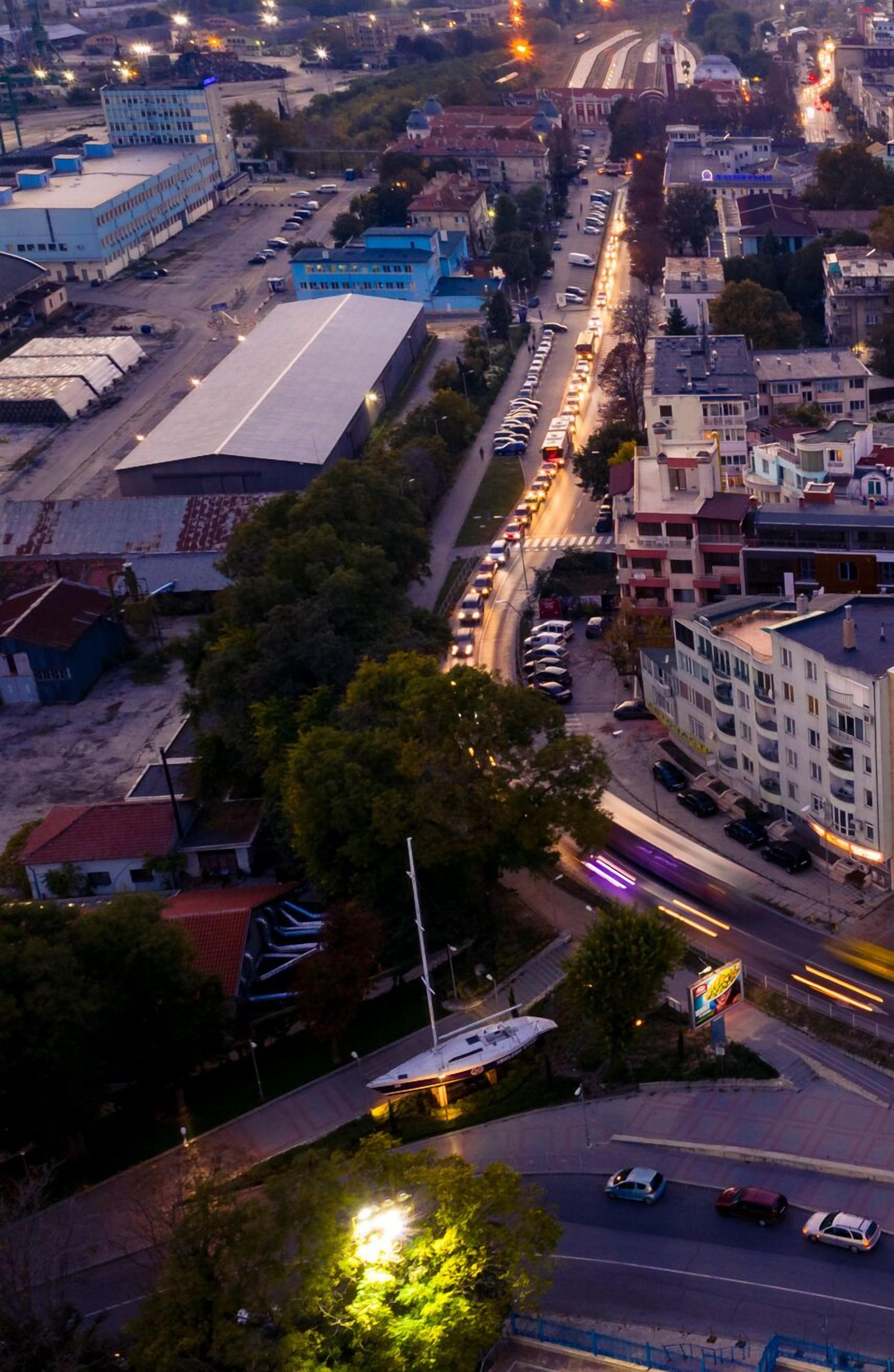 Vista aérea de un paisaje urbano con una extensa vía, edificios y automóviles estacionados.