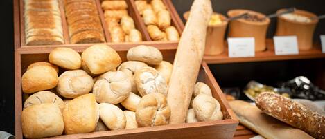 A wooden display case filled with various types of bread, including rolls, baguettes, and loaves.