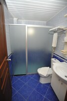 A bathroom with a shower enclosure, toilet, and sink.
