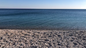 A pebbled beach with a clear view of the ocean.