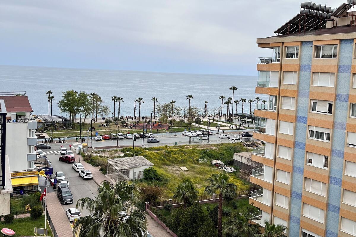Una zona urbana costera con un estacionamiento, edificios y vista al mar.