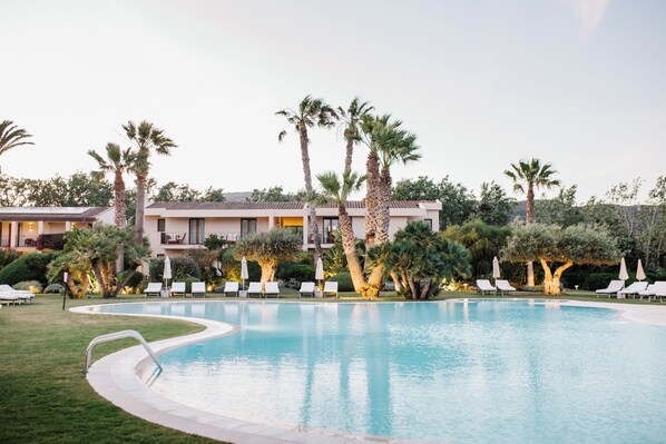 A swimming pool with lounge chairs and palm trees.