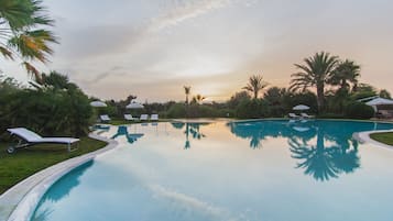Una piscina al aire libre, sillones reclinables de piscina