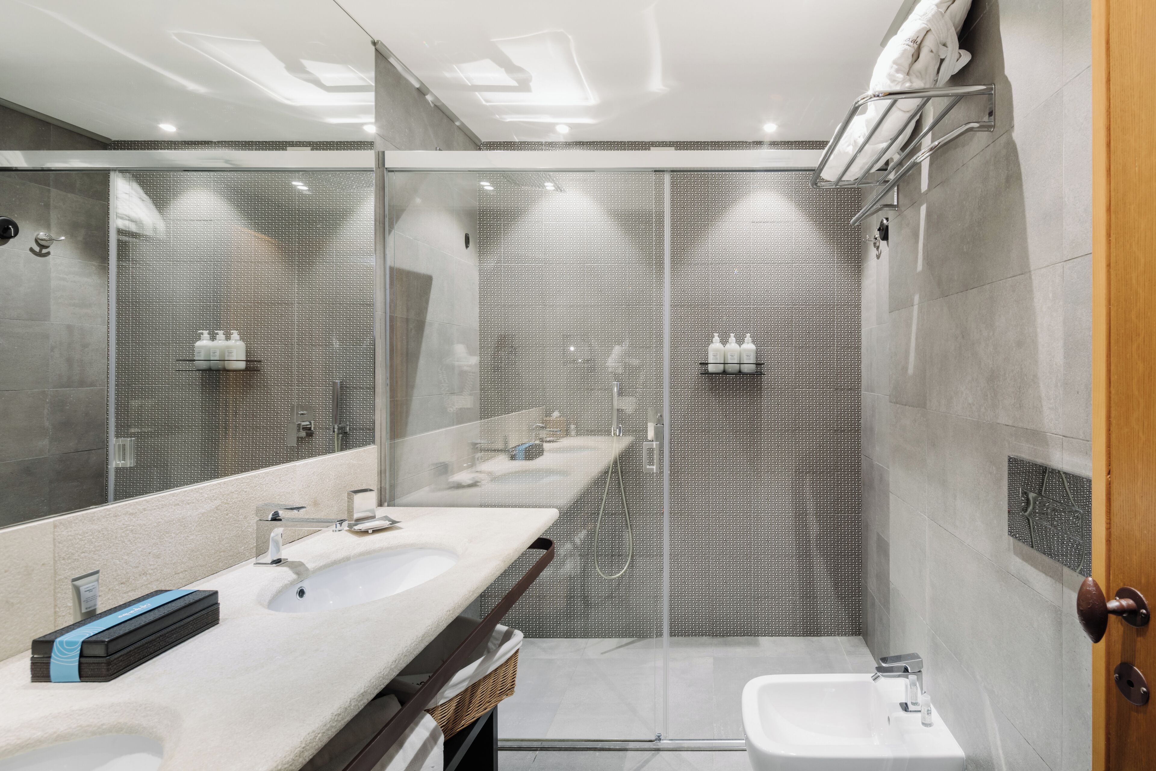 Une salle de bain moderne dotée d’une douche à parois de verre, de deux vasques et d’un grand miroir.