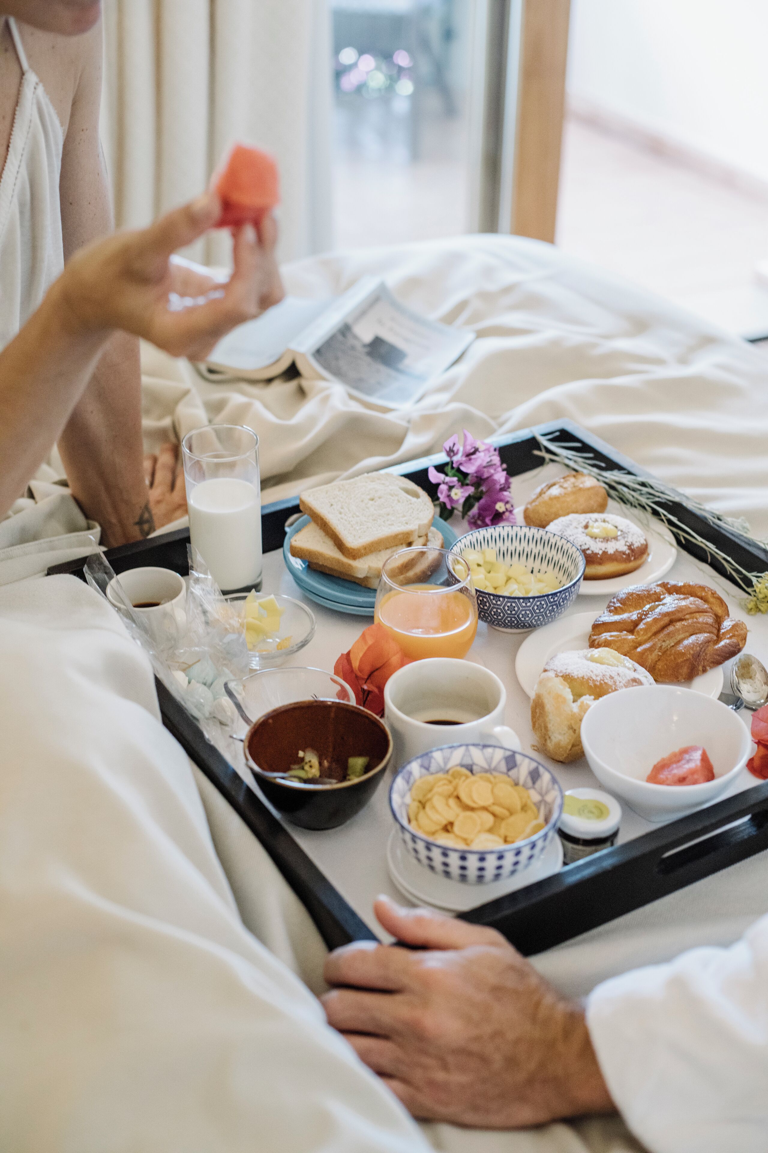 Un plateau de petit-déjeuner contenant divers aliments et boissons, posé sur un lit.