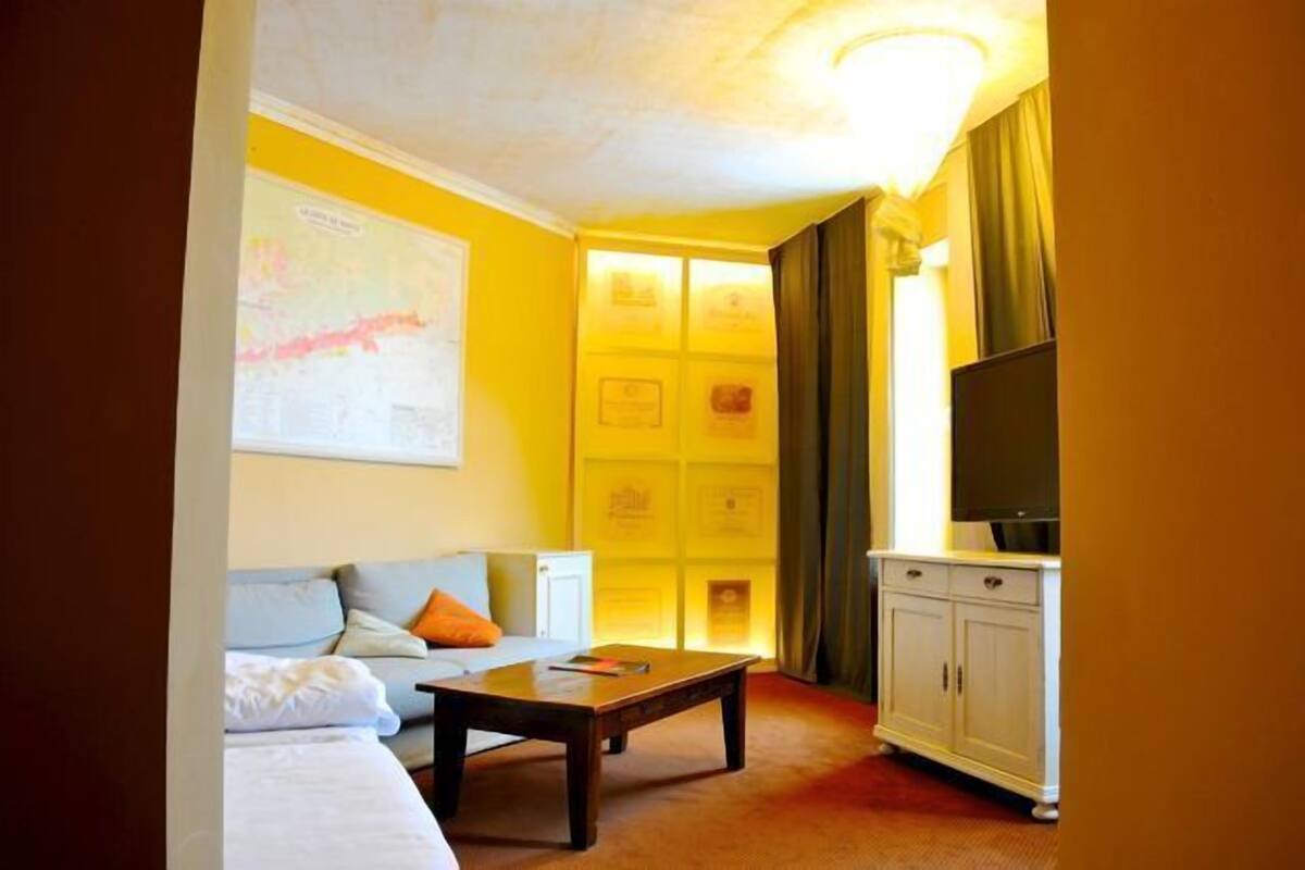 Habitación de hotel con cama, sofá, mesa de centro, televisor y armario.