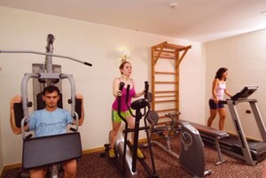 Ein Fitnessraum mit Trainingsgeräten, darunter Laufband, Crosstrainer und Kraftgeräte.