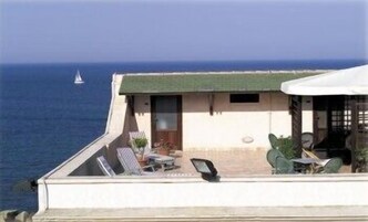 Una propiedad frente al mar con balcón que da al océano, con un pequeño rincón de estar con mesa y sillas.