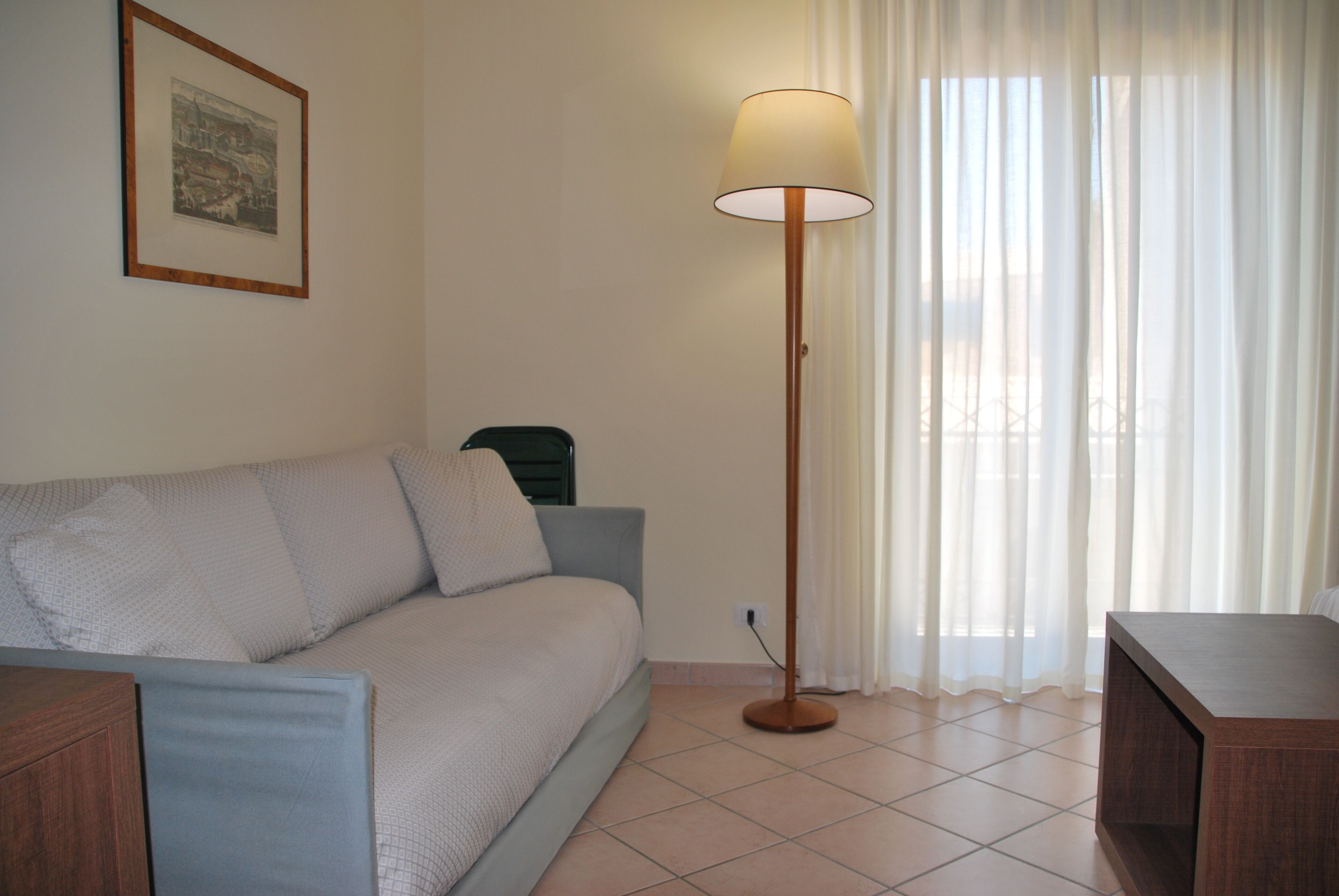 A living room with a sofa, a floor lamp, and a framed picture on the wall.