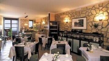 A restaurant with stone walls, tables set for dining, and a fireplace.