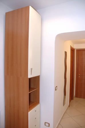 A room with a wooden wardrobe, a white cabinet, and a door.