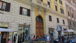 Un edificio con una entrada destacada, un letrero de una pizzería y una tienda de café.