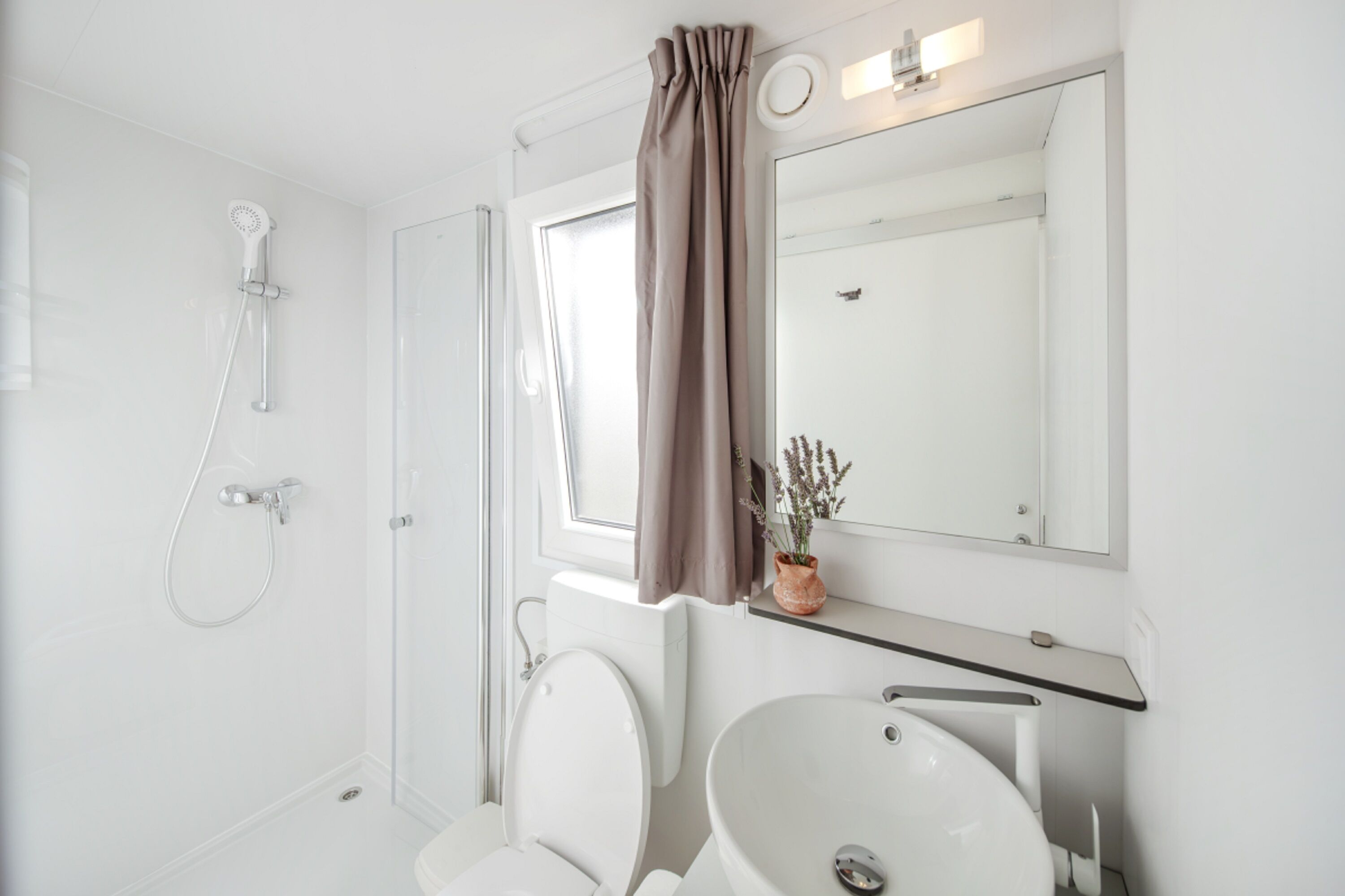 A modern bathroom with a shower, toilet, and sink.