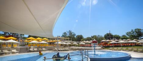 A swimming pool area with multiple lanes, umbrellas, and lounge chairs.