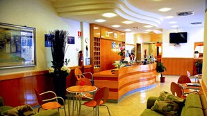 A hotel lobby with a reception desk, seating area, and a television. - Grazia Hotel (Sperlonga)