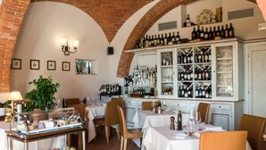 Un restaurante con arcos de ladrillo, una vitrina de vinos y mesas dispuestas para comer.