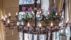 Eine Lobby mit einer Chandelieber, einem Empfangstresen und einem großen Fenster mit violetten Blumen.