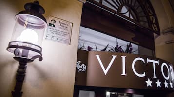 Un lampione d'epoca e un cartello con il nome “VICTOR” su una facciata di edificio.