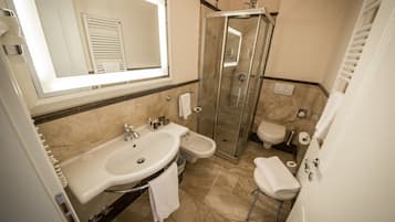 Un baño moderno con ducha de vidrio, lavamanos doble y retrete.