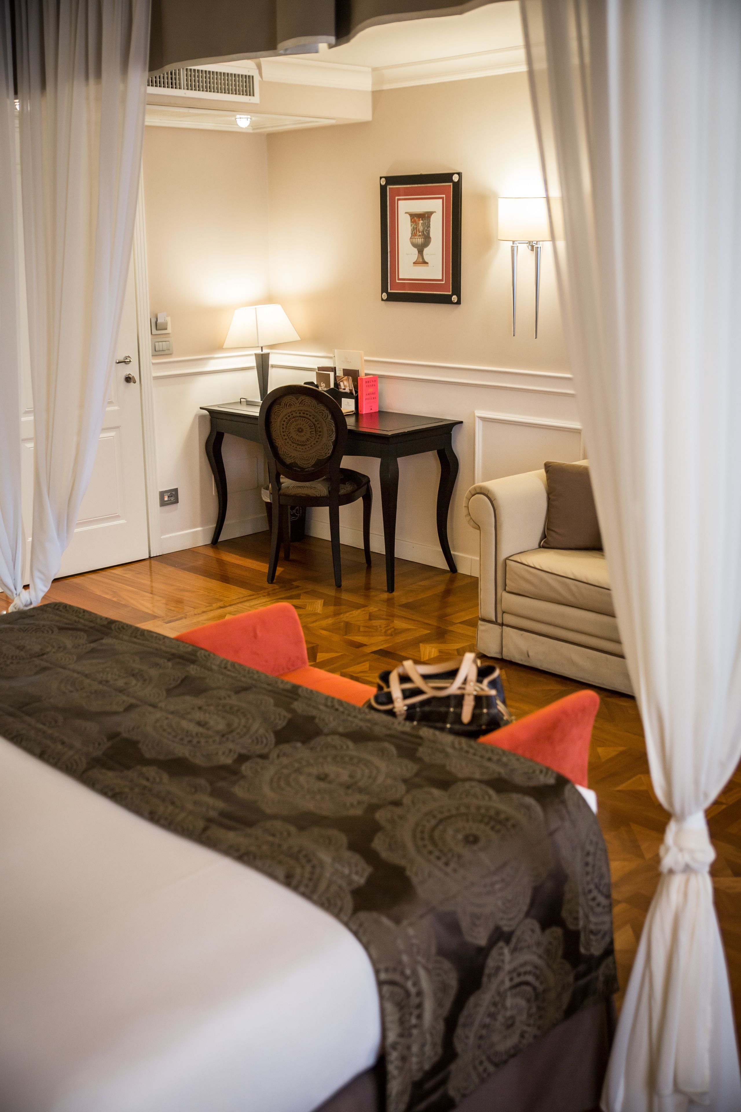 A hotel room with a bed, a desk, a chair, and a sofa.