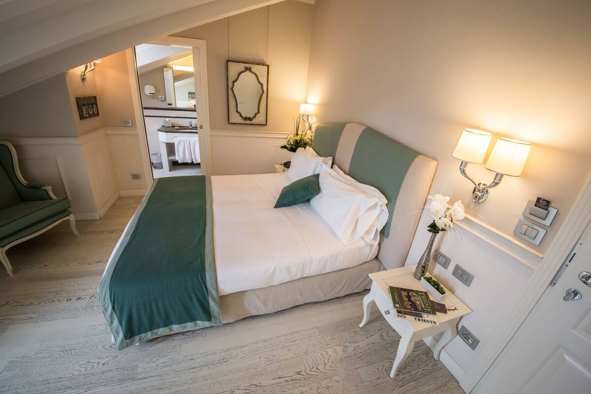 A neatly arranged bedroom with a bed, bedside table, and a small table with a vase and books.